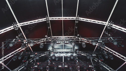 Professional stage lighting rig installed under a black canopy with multiple LED spotlights, moving heads, and metal trusses ready for a concert or live performance event setup