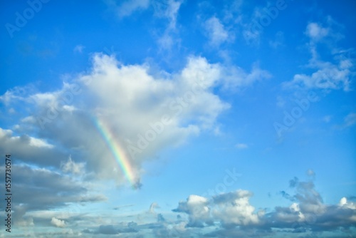 Sky replacement with a part of a colorful rainbow on the right side of clouds.