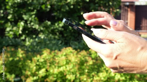 hands using a smartphone in the garden or public park background