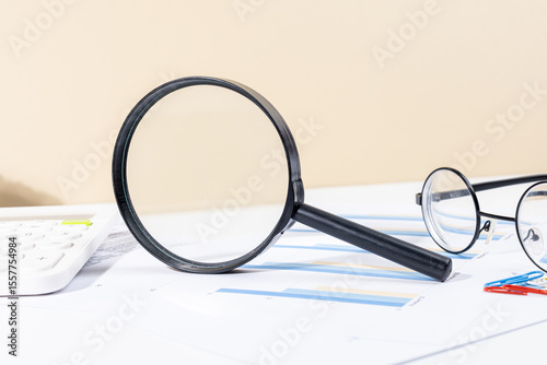 Fotografie Financial Charts and Graphs Analyzed with Magnifying Glass, Calculator, and Pen