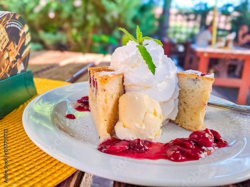 Cherry cake with ice cream and cherries with cream on a large white plate