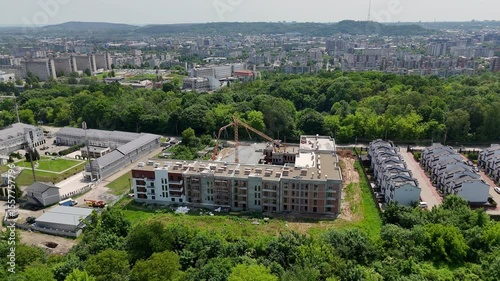 Urban Construction Site with Crane Surrounded by Residential Area, Mid-rise housing development near forest and city skyline