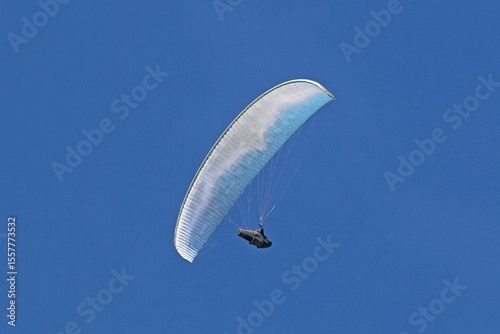Paraglider flying in a blue sky	