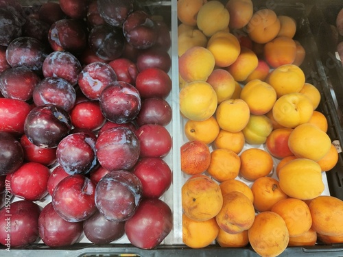 A display of fruit, including plums and peaches, is arranged in a tray