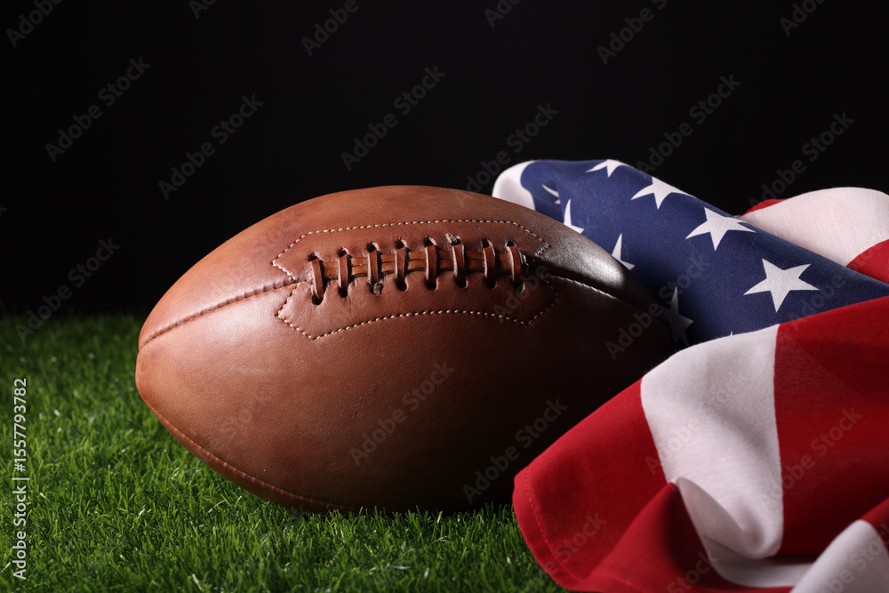 Obraz premium Football on a green field with white stripe and American flag behind