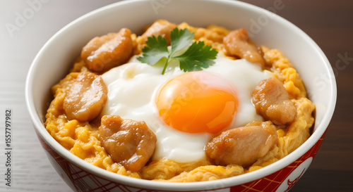 Close-up of a bowl of Oyako-don, a Japanese chicken and egg rice bowl, topped with a runny egg and parsley garnish.