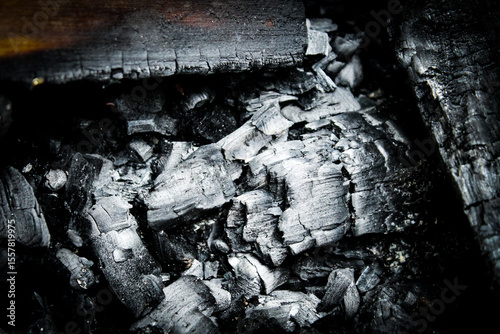 macro close-up of black charred wood, charcoal pieces, and ash abstract texture background. safety, environment, or art design element.