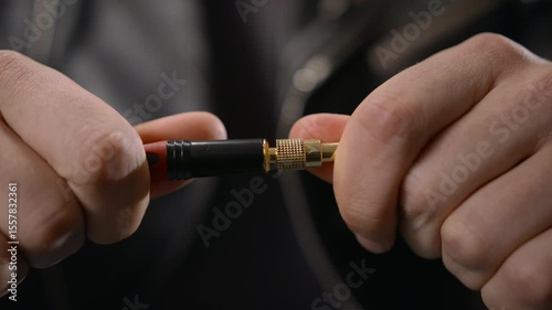Close-up of a male hand plugging a guitar cable into an amplifier