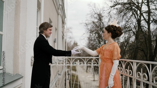 Tableau sur toile Nobleperson pair sharing tender moment on ornate balcony, wearing intricate 19th