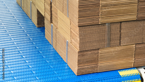 Elements of corton boxes are collected in stack. Conveyor line for the production of boxes. Machine cuts cardboard boxes from sheets of cardboard. Enterprise for the production package.