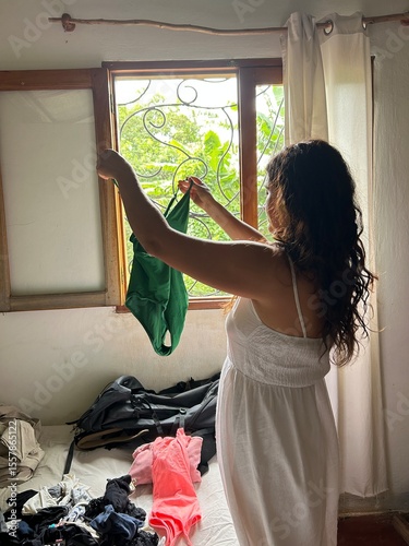 woman in her vacation accommodation, takes out her green one-piece swimsuit.