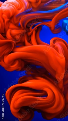 Vibrant red paint swirls dynamically through deep blue liquid creating mesmerizing abstract patterns with fluid motion and color mixing for creative design projects