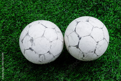 Two old used football or soccer ball on green grass
