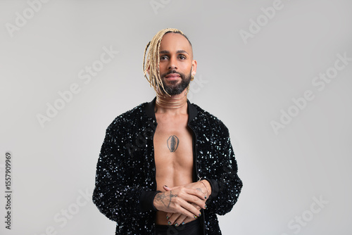Confident black gay man standing isolated on white background, dressed in a bold, black jacket with sequins. Exudes sense of pride and individuality. Diversity power of personal style