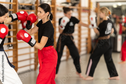 Sportive young girl training boxing in pair with his partner during sports classes