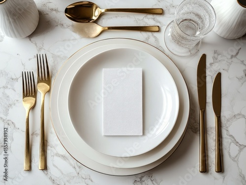 Elegant formal table setting with white plates on a marble surface and gold cutlery including forks, knives, spoons, alongside a clear drinking glass and white napkin