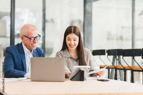 Wallpaper Mural Two businesspeople discussing work with laptop and documents in modern office, showing positive and engaged expressions Torontodigital.ca