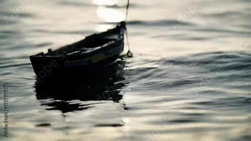 Small boat adrift on calm water with sunlight reflecting