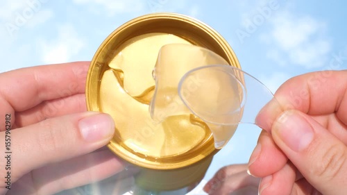 Woman takes out moisturizing eye patch from jar close-up top view.