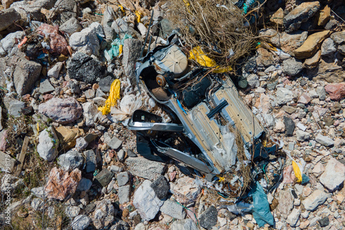 Overturned vehicle among rocky debris, emphasizing environmental impact and industrial waste. captivating view highlights destruction's stark contrast with rugged terrain.