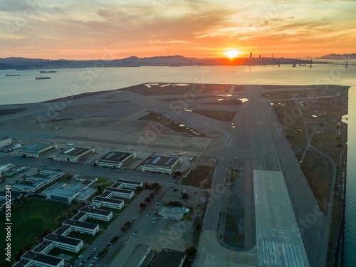 Bild auf Leinwand Aerial view of Alameda Naval Air Station runway at sunrise, with San Francisco skyline and Bay Bridge in the background, USA