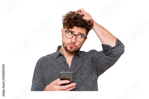 Confused young man scratching his head while looking at his smartphone