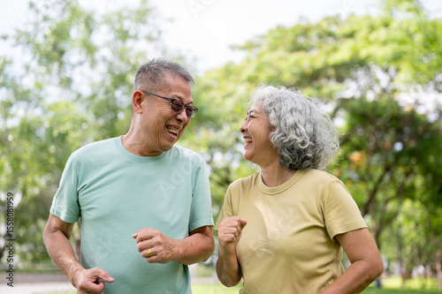 Glasses old man and old woman smiling or laughing while running or jogging together inside the park.