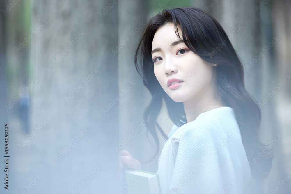 Fototapeta premium Smiling Asian Woman with Green Notebook Standing Outdoors