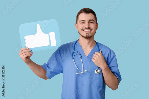 Handsome young happy male doctor with like icon on blue background
