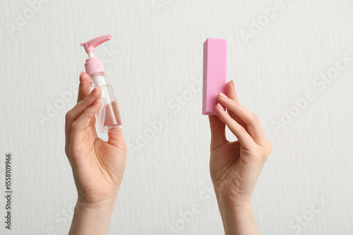 Quadro em tela Female hands with bottle of cuticle oil and buffer on white background