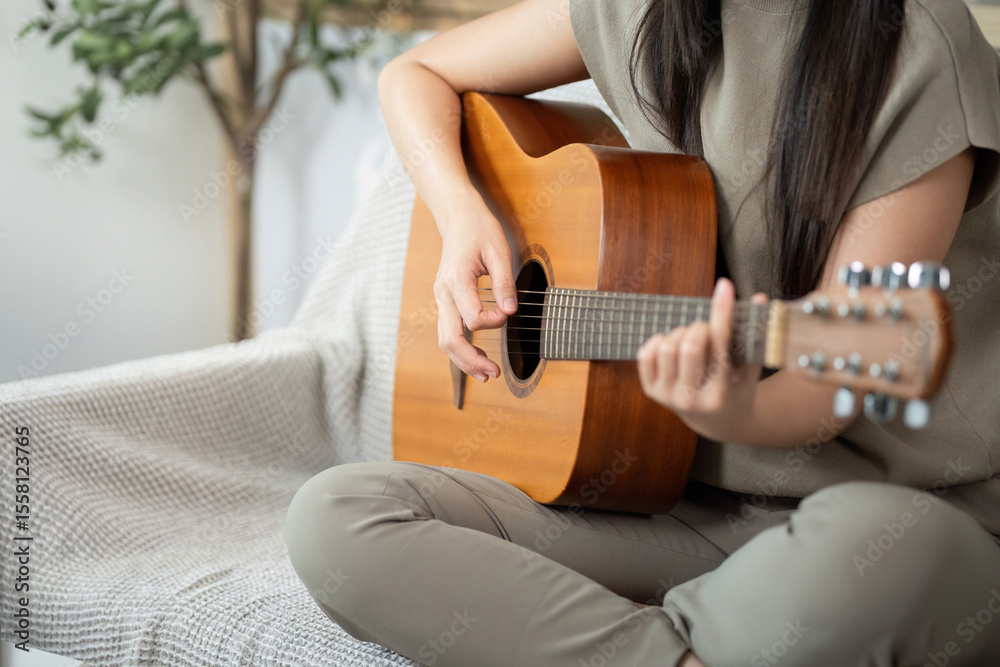 Fototapeta premium Music and Relaxation. Young woman playing acoustic guitar at home.