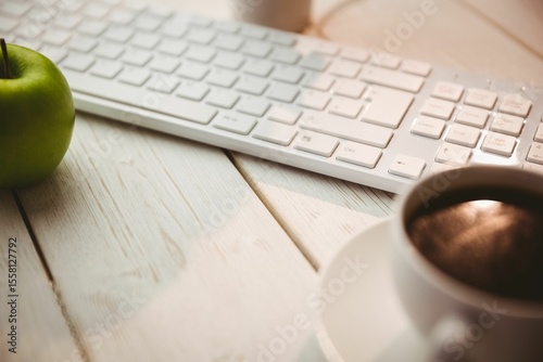 Keyboard with coffee and green apple on table