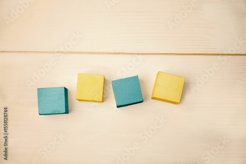 Flat design is showing four wooden blocks in row on wood surface, highlighting teal and yellow