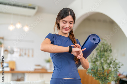 Papier peint Fitness woman holding yoga mat and look at smartwatch checking heart rate, calor