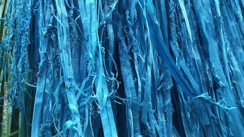 Colorful decorations made from plastic strings fluttering in the wind. The light movement creates a playful and festive atmosphere, adding charm to outdoor spaces or local celebrations.