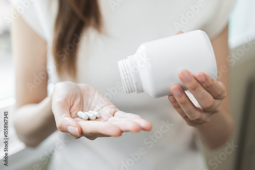 Sick asian young woman, girl holding tablet pill on hand pouring drug from medication bottle, painkiller medicine from stomach pain, head ache, pain for treatment, take drug or vitamin, health care.