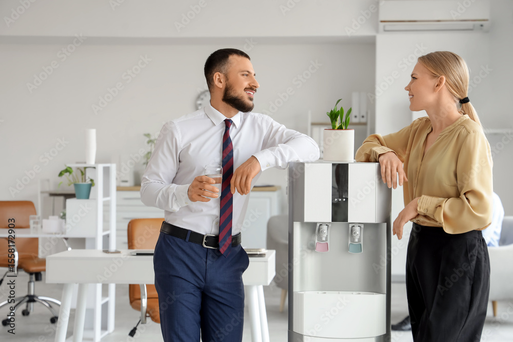 Fototapeta premium Young business colleagues near water cooler in office