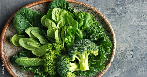 Fresh assortment of leafy greens and broccoli on a rustic plate against a textured background