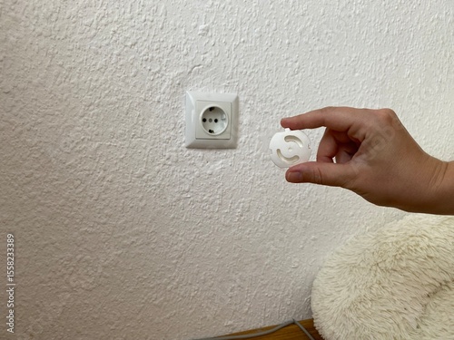Demonstration of childproof socket covers being inserted into a power outlet to prevent accidental electric shock.