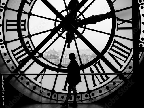 A human figure in silhouette stands out against a large clock, Paris, France, in black and white