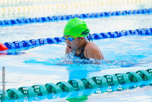 Swimmer child swims breaststroke swimming style in a race swimming pool. Water sports and competition, learning to swim classes for children.