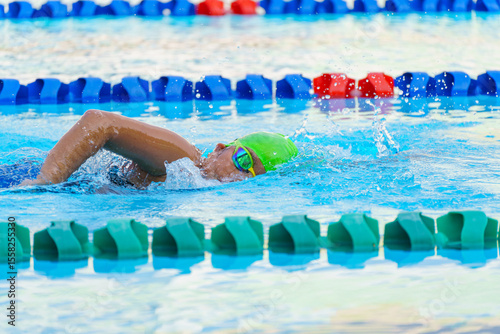 Swimmer child swims freestyle swimming style in a race swimming pool. Water sports and competition, learning to swim classes for children.