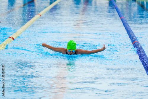 Swimmer child swims butterfly swimming style in a race swimming pool. Water sports and competition, learning to swim classes for children.