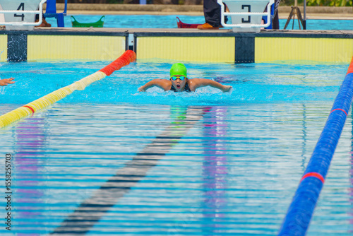 Swimmer child swims butterfly swimming style in a race swimming pool. Water sports and competition, learning to swim classes for children.