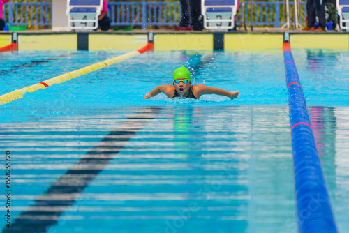 Swimmer child swims butterfly swimming style in a race swimming pool. Water sports and competition, learning to swim classes for children.