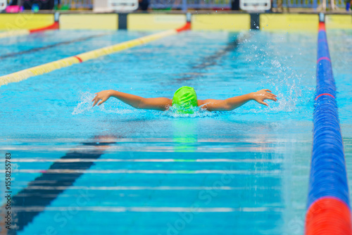 Swimmer child swims butterfly swimming style in a race swimming pool. Water sports and competition, learning to swim classes for children.