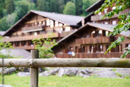 Visitors enjoy the peaceful atmosphere near charming wooden chalets surrounded by vibrant nature in summer.