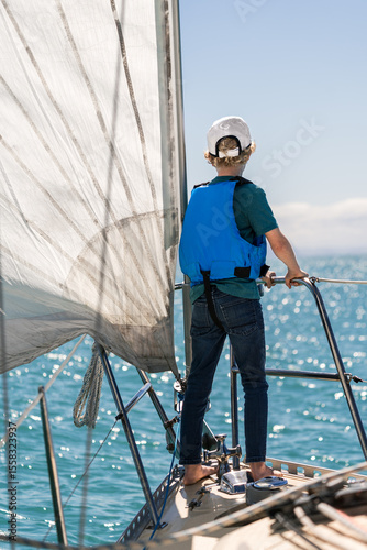 Child in hat and lifejacket on sailboat on sunny day