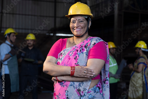 Photography Portrait of beautiful young woman in hardhat confidently at camera enjoying work