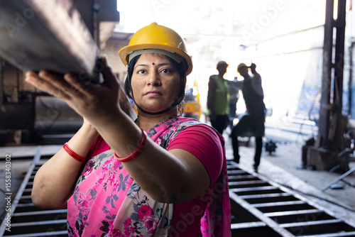 Photography Female iron Factory Worker at work moving iron poles.